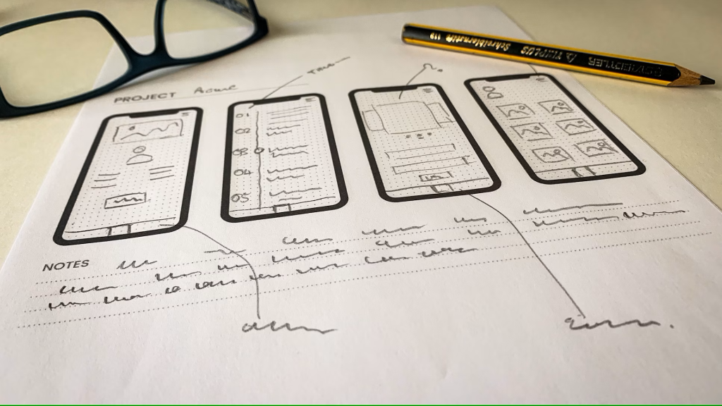 Croquis de wireframes mobiles annotés à la main, illustrant la phase de conception d’un projet numérique