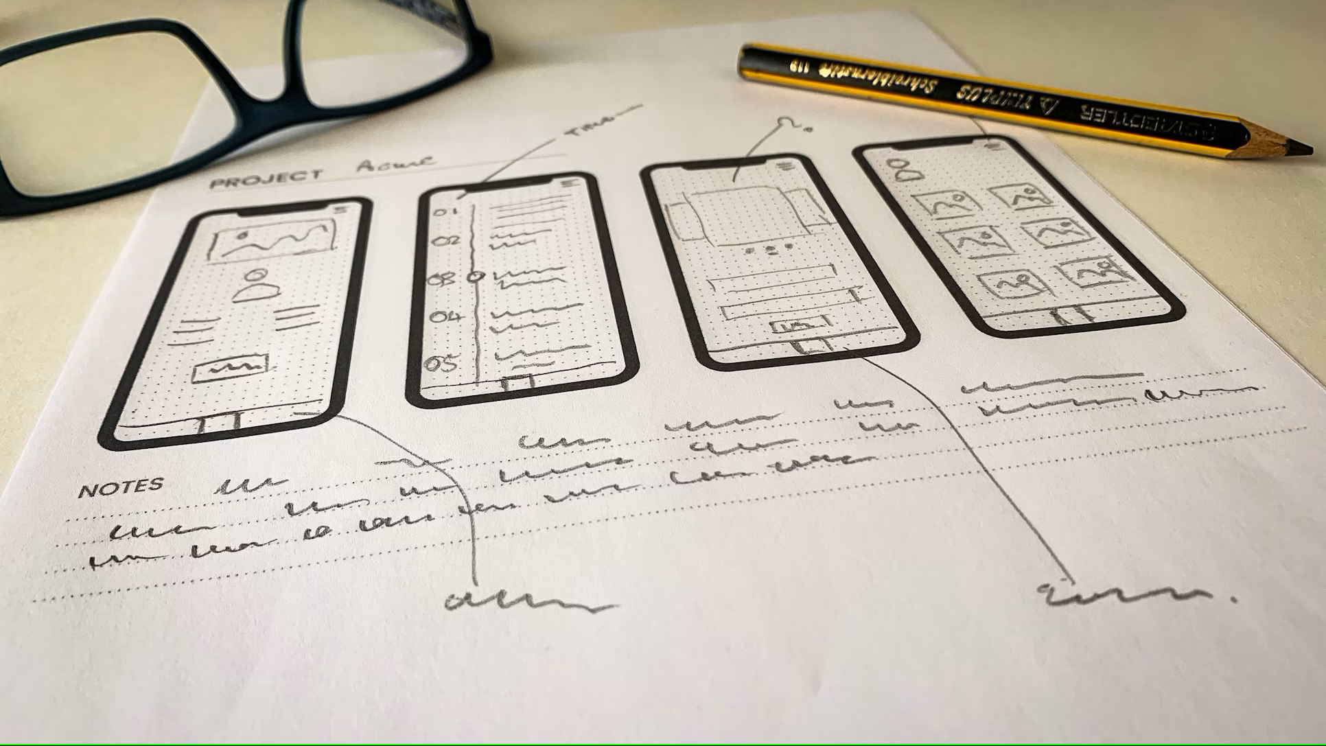 Croquis de wireframes mobiles annotés à la main, illustrant la phase de conception d’un projet numérique