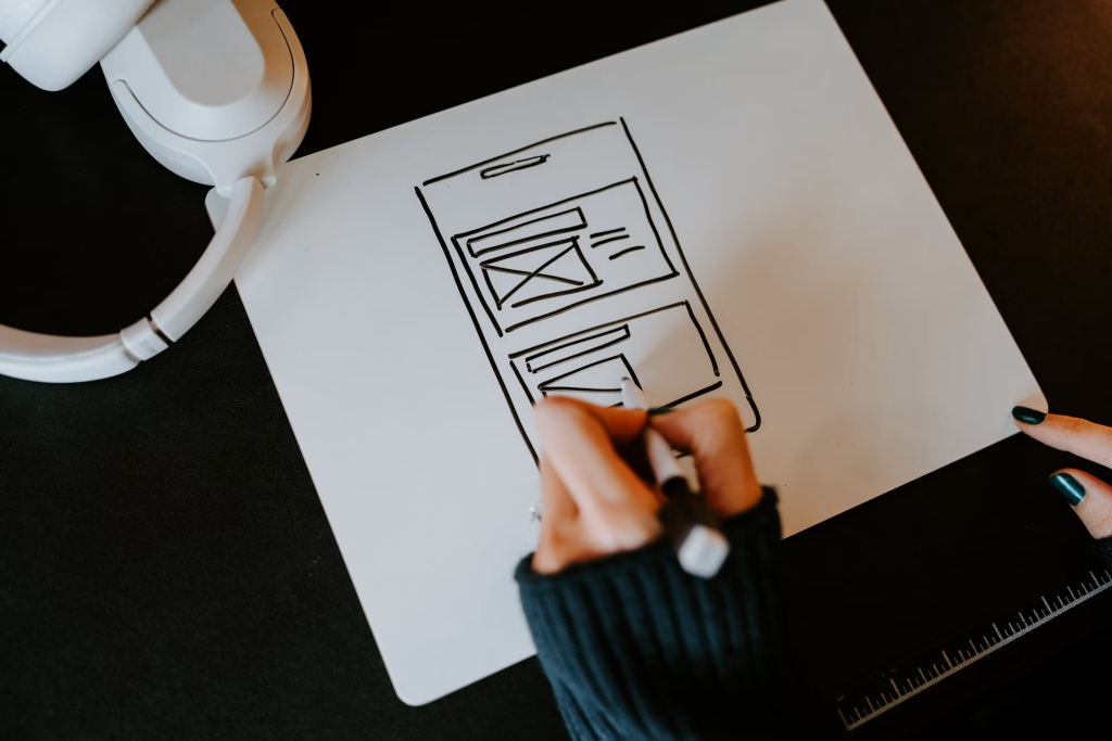Personne dessinant une maquette de site web à la main sur un tableau blanc
